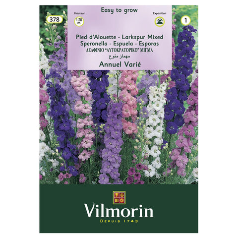 En esta imagen se ve un sobre de semillas de flores Espuela Imperial de variedad de colores. Marca Vilmorin. En la foto del envase aparecen flores Espuela Imperial de colores morado oscuro, morado claro, rosado y blanco.